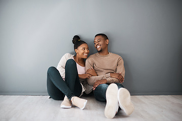 Image showing Homeowner, love and beginning with a black couple sitting together in their new home on a gray wall background. Real estate, room and mortgage with a man and woman on the floor after moving house