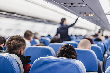 Image showing Stewardess walking the aisle of commercial airplane.