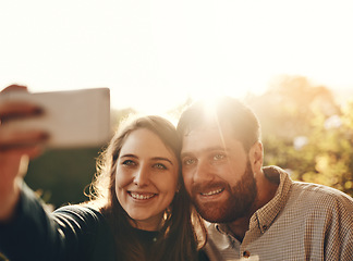 Image showing Selfie, smile and couple in nature with a phone for social media, memory and happiness. Flare, happy and young man and woman with a photo on a mobile while on a date in a park for love in marriage