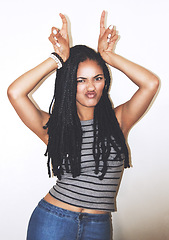 Image showing Portrait, hand gesture and horns with a black woman posing in studio on a gray background for quirky fun. Face, fashion and beauty with an attractive young female making a devil horn sign with hands