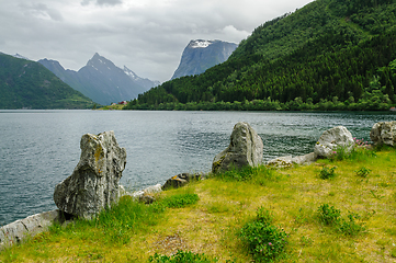 Image showing Large rocks by the sea and mountain peaks above the sea