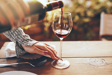 Image showing Hands, pouring wine and at dinner party for celebration, relax and enjoy beverage. Woman, glass and red alcohol for dining table, for lunch and brunch for holiday, on break and calm in summer event.