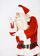 Image showing Father Christmas in studio pointing to white background for marketing, branding or advertising mockup space. Product placement, santa claus or old man shows retail sales discount offer or promo deal