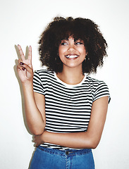 Image showing Peace, sign and black woman with smile, excited and casual against a gray studio background. Young female, hand gesture and girl being silly, goofy and playful with trendy, edgy and stylish look.