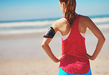 Image showing Beach, fitness and woman athlete by the sea looking at ocean back view before running workout. Health, wellness and freedom feeling outdoor in summer for exercise, sports and headphones with music