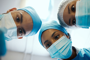 Image showing Surgery, face mask and surgeon team during covid working on medical operation for hospital healthcare help. Emergency support, doctors teamwork collaboration and bottom view of man and women helping