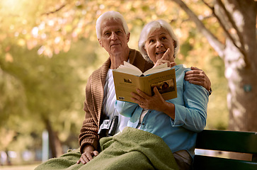 Image showing Couple, elderly and reading a book in park, travel and outdoor during retirement with relationship and spending quality time together. Man, woman and relax on park bench, talk with view in New York.