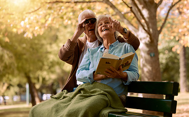 Image showing Park, bench and binoculars with a senior couple birdwatching together outdoor in nature during summer. Spring, love and book with a mature man and woman bonding while sitting in a garden for the view