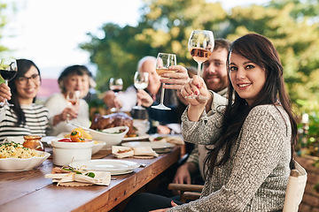 Image showing Toast, dinner and family with a group of people enjoying a meal together while drinking alcohol outdoor. Portrait, party and cheers with a female and relatives bonding in festive celebration