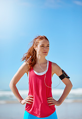 Image showing Runner woman, beach and sky with earphones for music, workout motivation and training by ocean. Athlete girl, exercise and running for wellness by sea waves with focus for fitness, health and outdoor