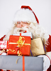 Image showing Wink, Christmas gifts and portrait of Santa Claus in studio on white background. Xmas, costume and man with glasses holding pile of presents for happy December holiday celebrations or festive party