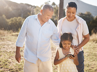 Image showing Phone, family and nature with a girl and grandparents outdoor together during summer vacation. Social media, love and care with a senior man and woman bonding with their female grandchild outside