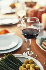 Image showing Closeup, glass and wine on table at dinner, restaurant or house for celebration, holiday or party. Red wine, alcohol and vegetables in dining room for thanksgiving, Christmas or fine dining in home