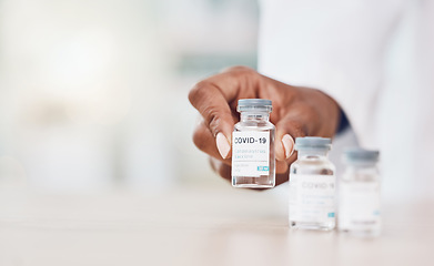 Image showing Hand, woman and doctor with covid vaccine bottle and working in her hospital office. Healthcare expert with a bottle, wellness or corona medicine in a medical research clinic for safety from covid 19