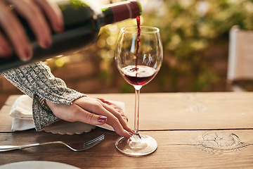 Image showing Glass, bottle and hand of woman pouring wine at a table, calm and content while enjoying free time on a patio. Red wine, hands and lady relax with luxury drink, enjoy a relaxing weekend alone at home