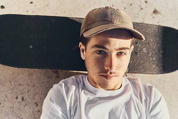 Image showing Skateboard, portrait and young man chilling at a skate park alone in the city while on a break. Sports, relax and guy resting while skateboarding training for a competition at a park in a urban town.