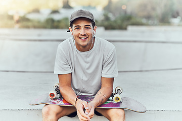 Image showing Young man, skateboard and skater with music at urban skate park, youth and recreation with earphones for audio streaming. Happy, portrait, and gen z outdoor with skating practice and fitness.