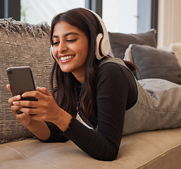 Image showing Woman, phone and headphones for listening to music online for happiness, calm and peace while streaming on audio app on home and living room sofa. Female watching video or movie on internet with 5g