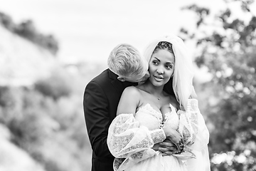 Image showing Happy newlyweds hugging against the backdrop of a beautiful mountain landscape, a guy kissing a girl, black and white version