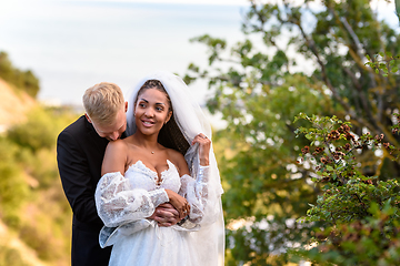 Image showing Newlyweds hug against the backdrop of a beautiful landscape, the guy kisses the shoulder of a girl who has a happy look