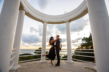 Image showing A young couple hugs in a gazebo against the backdrop of a beautiful landscape