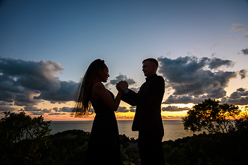 Image showing Happy young couple holding each other's hands in backlight against sunset background