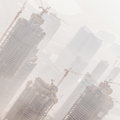 Image showing Skyscrappers construction site with cranes on top of buildings.