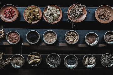 Image showing Various spices displaied on small ceramic and metal plates on black wooden background.