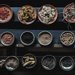 Image showing Various spices displaied on small ceramic and metal plates on black wooden background.