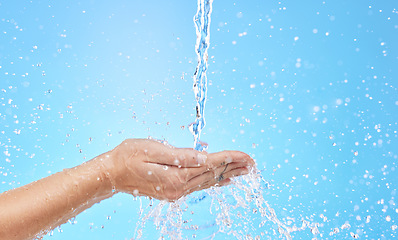 Image showing Hand, water and cleaning with a splash in studio on a blue background for hygiene or hydration. Mockup, health and wellness with a female washing under a water splash in the bathroom for skincare