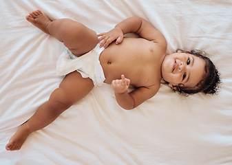 Image showing Happy baby, smile and relax on bed in family home bedroom for diaper change, bedtime or healthy childcare. Child, happiness and body care in disposable nappy or kids portrait from above in nursery