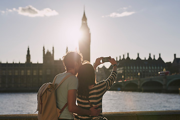 Image showing Phone, selfie and couple by the big ben in London on vacation, adventure or holiday together. Travel, building and young tourist man and woman taking a picture on a smartphone in the city in England.