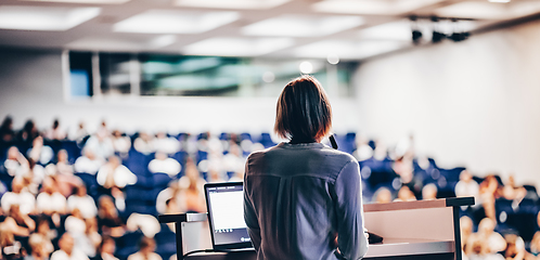 Image showing Female speaker giving a talk on corporate business conference. Unrecognizable people in audience at conference hall. Business and Entrepreneurship event.