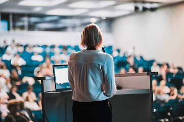 Image showing Female speaker giving a talk on corporate business conference. Unrecognizable people in audience at conference hall. Business and Entrepreneurship event.