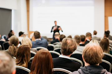 Image showing Speaker giving a talk in conference hall at business event. Rear view of unrecognizable people in audience at the conference hall. Business and entrepreneurship concept.