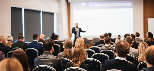 Image showing Speaker giving a talk in conference hall at business event. Rear view of unrecognizable people in audience at the conference hall. Business and entrepreneurship concept.