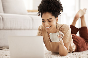 Image showing Laptop, coffee and relax with a woman lying on the floor in her home living room over the weekend. Computer, social media and internet with a female typing or reading an email while in her house