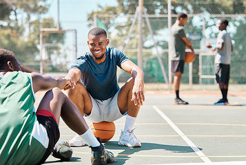 Image showing Sports, basketball and friends, men relax and fist bump on basketball court in happy summer. Friendship, teamwork and basketball player sitting on ground with friend and ball in community playground.