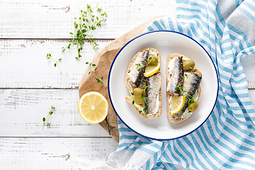 Image showing Sardines sandwiches on a white wooden background. Mediterranean food. Top view