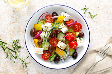 Image showing Greek salad. Vegetable salad with feta cheese, tomato, olives, cucumber, red onion and olive oil. Healthy vegetarian mediterranean diet food. Top view