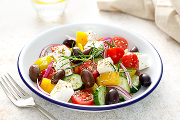 Image showing Greek salad. Vegetable salad with feta cheese, tomato, olives, cucumber, red onion and olive oil. Healthy vegetarian mediterranean diet food