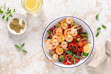 Image showing Shrimp kebab roasted on skewers and fresh vegetable salad, top view