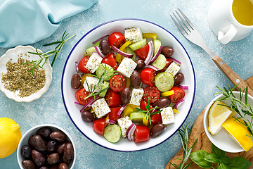 Image showing Greek salad. Vegetable salad with feta cheese, tomato, olives, cucumber, red onion and olive oil. Healthy vegetarian mediterranean diet food. Top view