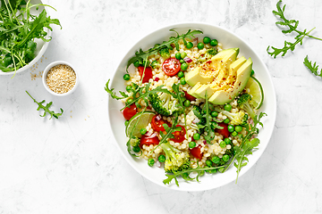 Image showing Couscous salad with broccoli, green peas, tomatoes, avocado and fresh arugula. Healthy natural plant based vegetarian food for lunch, israeli cuisine, top view