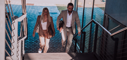 Image showing Modern business couple after a long day's work, walking together towards the comfort of their home, embodying the perfect blend of professional success and personal contentment.