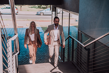 Image showing Modern business couple after a long day's work, walking together towards the comfort of their home, embodying the perfect blend of professional success and personal contentment.