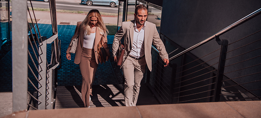 Image showing Modern business couple after a long day's work, walking together towards the comfort of their home, embodying the perfect blend of professional success and personal contentment.