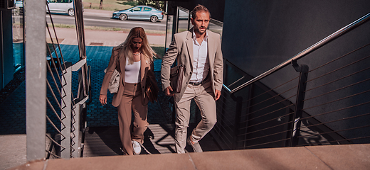 Image showing Modern business couple after a long day's work, walking together towards the comfort of their home, embodying the perfect blend of professional success and personal contentment.