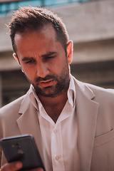 Image showing A businessman using his smartphone outdoors, showcasing the seamless integration of technology and mobility in modern professional life.