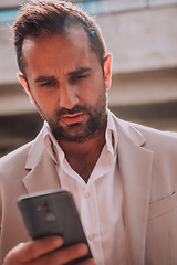 Image showing A businessman using his smartphone outdoors, showcasing the seamless integration of technology and mobility in modern professional life.